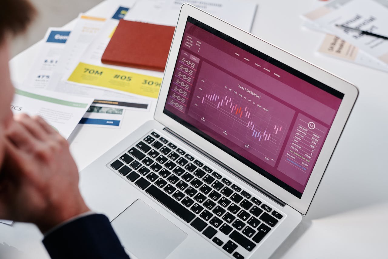 Businessperson reviewing data analytics on a laptop screen in an office setting.